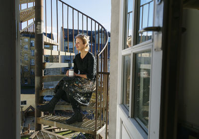 Woman sitting on fire stairs