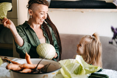 Happy vegan family mom and baby daughter cooking together and having fun on kitchen. family cooking