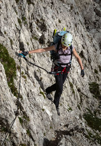 High angle view of woman climbing on mountain against sky