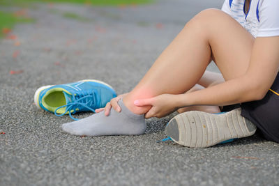 Low section of woman suffering from pain on road