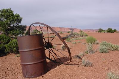 Rusty wheel on field against sky