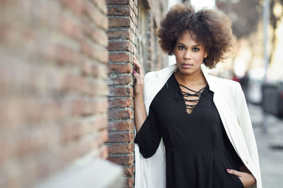 Portrait of young woman leaning against wall