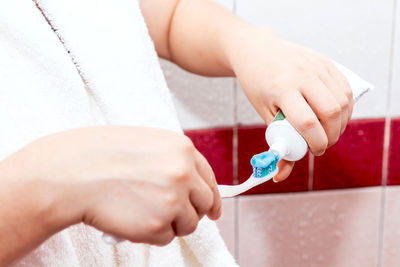 Midsection of woman putting toothpaste on brush