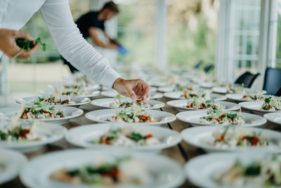 Midsection of man serving food in plates on table at wedding ceremony