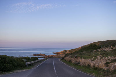 Empty road by sea against sky