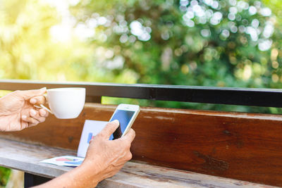 Cropped image of woman with mobile phone and coffee at table