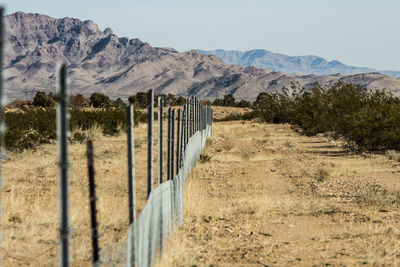 Fence on field against mountains