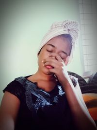 Portrait of a young woman against wall at home