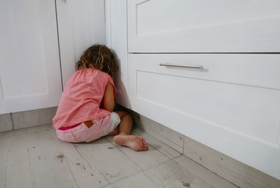 Rear view of girl hiding in kitchen