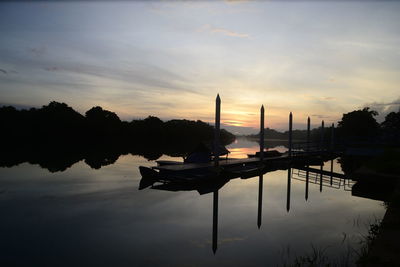 Silhouette of boat in lake at sunset