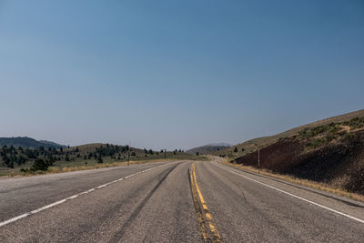 Empty road along landscape against clear sky