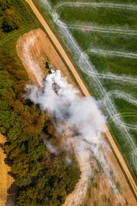 Aerial view of a tractor spreading lime on fields to improve soil quality after the harvest. 