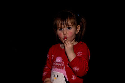 Close-up portrait of girl against black background