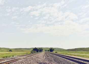 Road by railroad tracks against sky