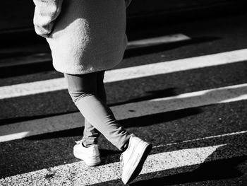 Low section of woman walking on road