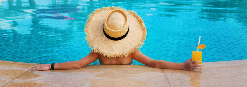 Rear view of woman with arms raised in swimming pool