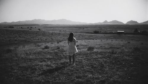 Rear view of woman standing on field against clear sky