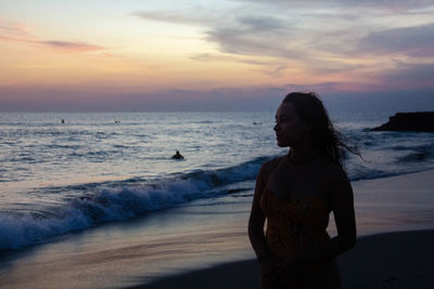 Man standing on beach against sky during sunset