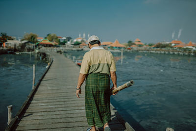 Rear view of man standing on pier