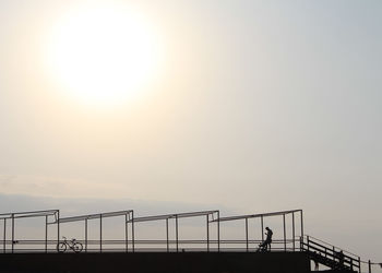 Man standing on railing against clear sky during sunset