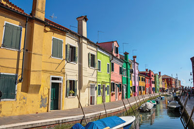 Colorful buildings and boats in front of a canal at burano, a little town full of canals in italy.