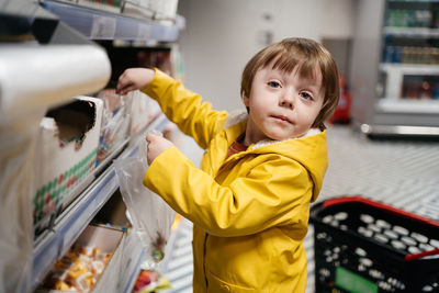 Child in the market with a grocery cart, puts sweets in a bag