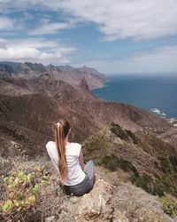 Rear view of woman on mountain looking at sea