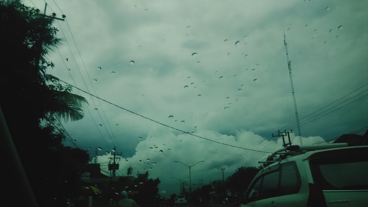 sky, transportation, window, transparent, weather, mode of transport, glass - material, car, cloud - sky, wet, rain, vehicle interior, drop, land vehicle, cloudy, tree, indoors, silhouette, cloud, dusk