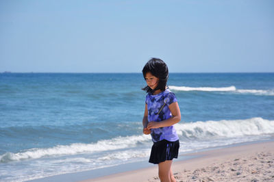 Full length of girl standing on beach against clear sky