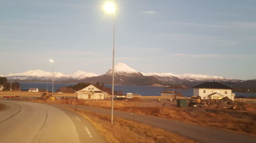 Road by mountains against sky during winter