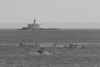 People kayaking in sea against clear sky