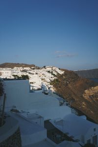 High angle view of townscape by sea against clear blue sky