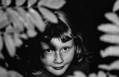 Close-up portrait of girl smiling amidst leaves