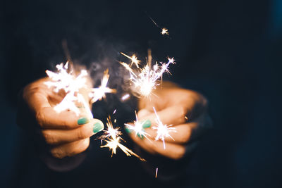 Woman holding burning sparklers at night