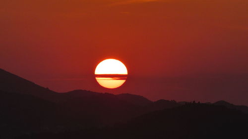 Silhouette mountains against orange sky