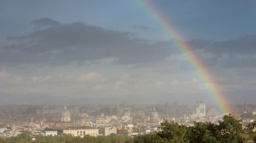 Rainbow over city buildings against sky