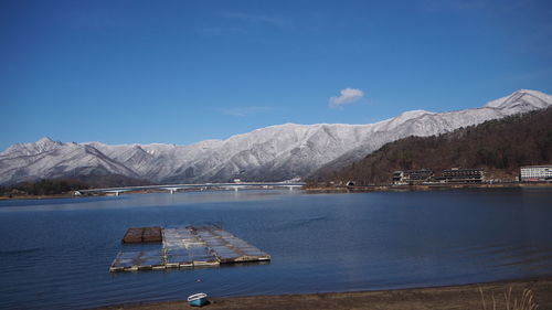 Scenic view of lake by snowcapped mountains against sky