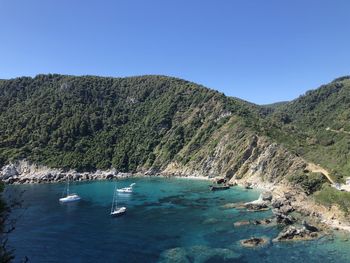 Scenic view of sea and mountains against clear blue sky