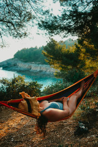 Side view of woman relaxing on land against sky