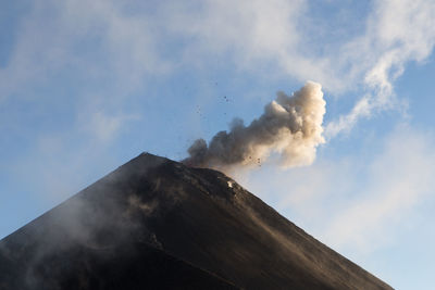 Low angle view of smoke emitting from volcanic mountain against sky