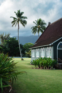 Scenic view of typical tropical building against palm tree and moody sky