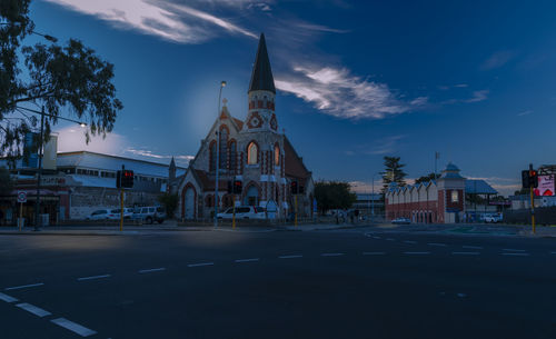 Road by buildings against sky in city