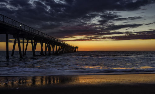 Pier over sea against dramatic sky