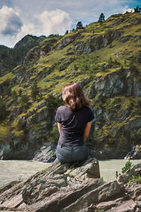 Rear view of woman sitting on rock
