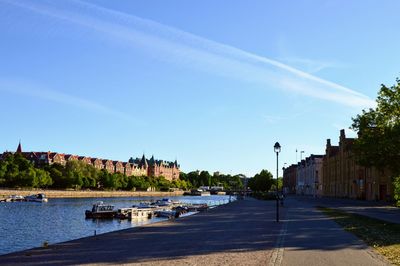 Cars on street by river against sky in city