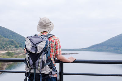 Rear view of man standing over lake against sky