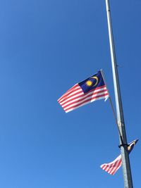 Low angle view of flag flags against clear blue sky