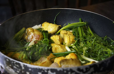 Delicious turmeric fish served on pot with fresh greenery