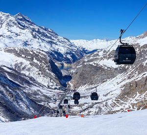 Overhead cable car on snowcapped mountains against sky