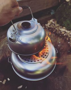 Close-up of hand holding tea kettle on stove